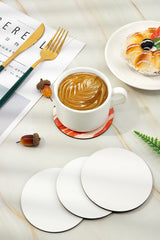 Blank sublimation coasters on marble table with coffee, pastry, and gold cutlery