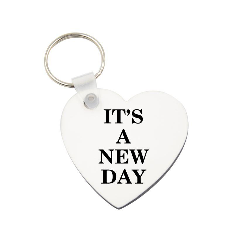 Heart-shaped sublimation blank keyring with 'It's a New Day' text, ideal for laser engraving.