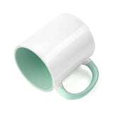 Angled view of 11oz ceramic mug with mint green inner and handle, showcasing glossy white coating for sublimation customization.