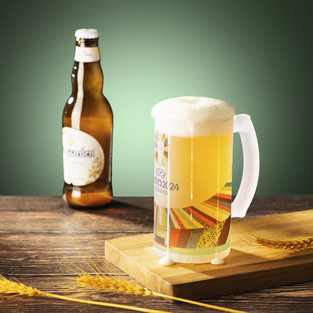 Frosted sublimation beer stein with colorful printed design beside beer bottle on wooden table